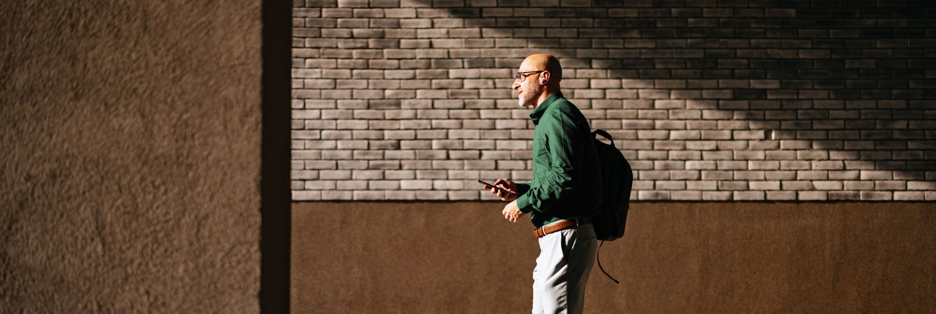 Man wearing business casual clothes walking holding his phone