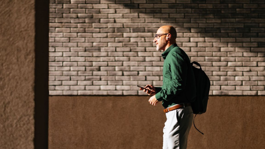 Man wearing business casual clothes walking holding his phone