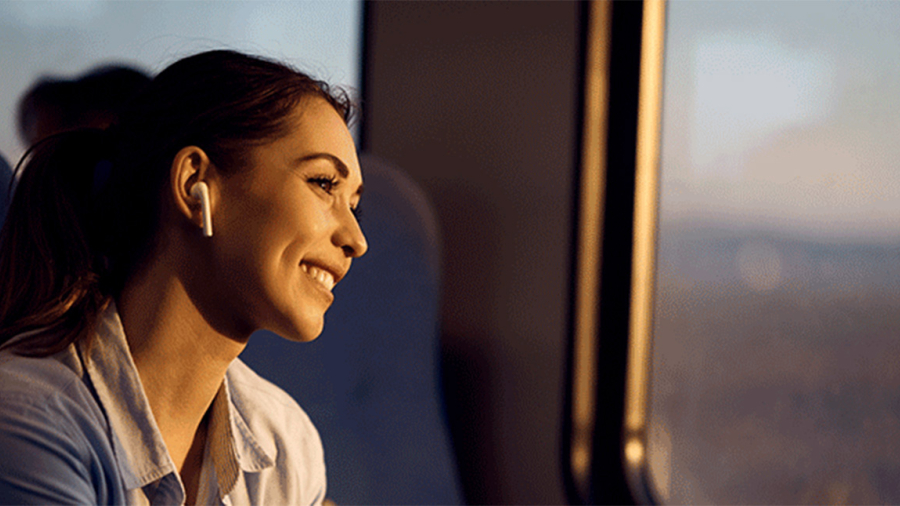 Femme souriante regardant par la fenêtre d'un train