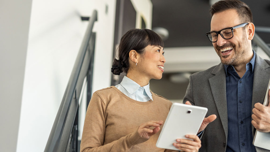 A professional woman and man walking down the stairs holding tablets